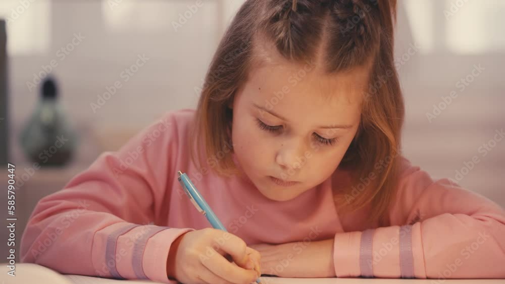 Concentrated preschooler writing in notebook, doing homework, home education Concentrated preschooler writing in notebook, doing homework, home education