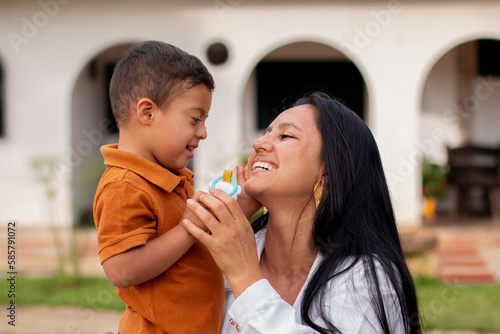 Loving mother affectionately holds her son with Down Syndrome who looks at her with love