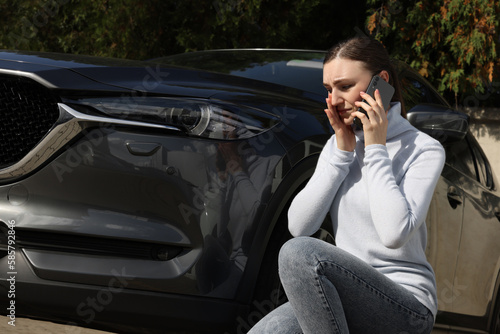 Stressed woman talking on phone near car with scratch outdoors © New Africa