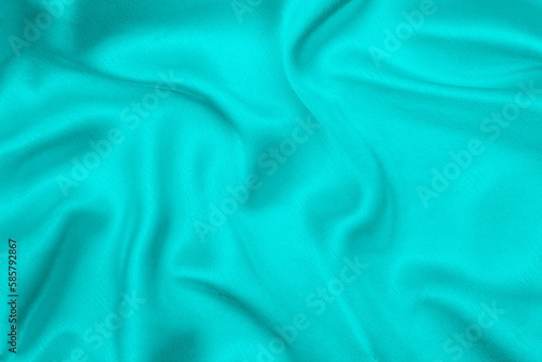 Satin beautiful fabric in turquoise color lies with drapery.