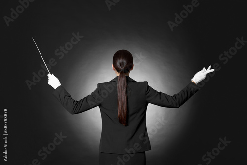 Professional conductor with baton on black background, back view