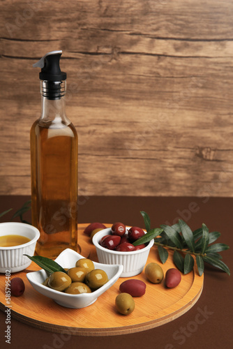 Oil, olives and tree twig on brown table