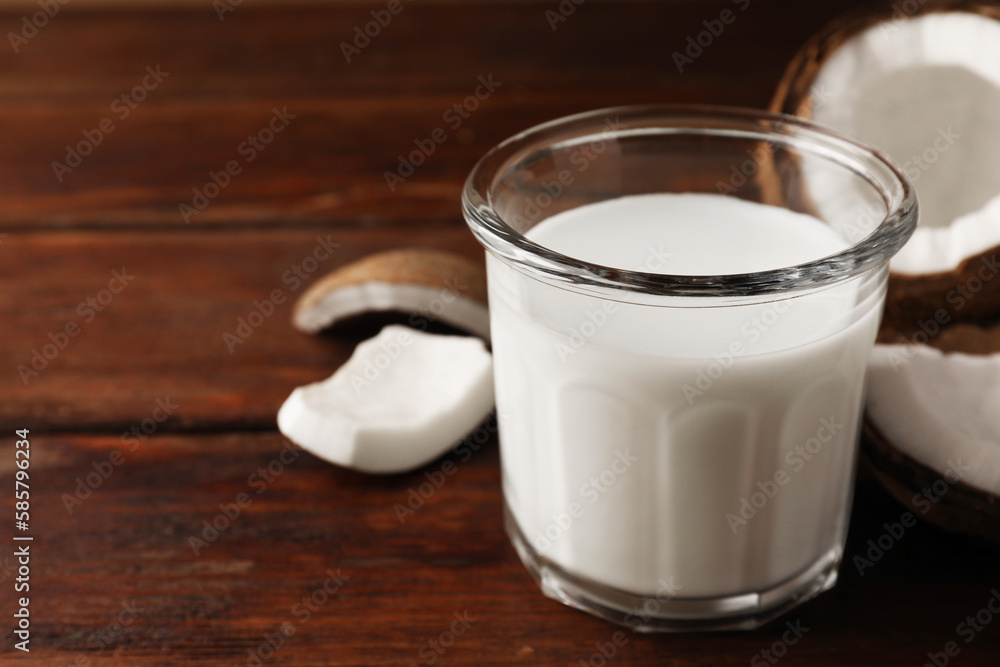 Glass of delicious vegan milk and coconut pieces on wooden table, space for text Glass of delicious vegan milk and coconut pieces on wooden table, space for text