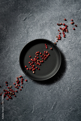 Ziarna czerwonego pieprzu na talerzyku na ciemnym tle Czerwony pieprz Red peppercorns on a plate on a dark background