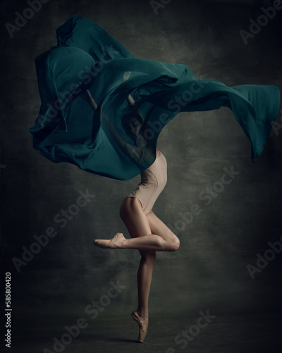 Fototapeta Naklejka Na Ścianę i Meble -  Shot of professional ballerina dancing in beige bodysuit with fabric isolated over dark green background