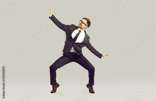 Work day is over let's go home. Happy office worker having fun because weekend starts now. Full body length cheerful joyful funny excited business man in suit dancing isolated on light gray background