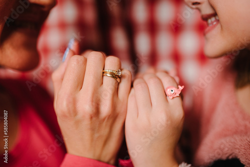 Hands of mother and daughter with rings. Mom hold hands of kid girl  giving supporting at home. Sincere different generations family sharing secrets. Tender moment together  show love. Closeup hands.