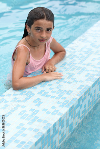 A beautiful young girl in the swimming pool. Adorable little girl is enjoying her time on a sunny day.  Traveling and vacation concept
