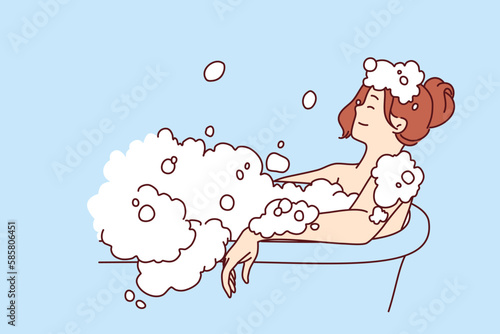 Carefree woman relaxes lying in bath with foam and warm water after hard day at work or long walk. Concept of water spa treatments for relaxation and wellness or for skin and body care 