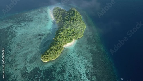 Aerial Footage. Descending through clouds over a tropical island surround by shallow coral reefs photo