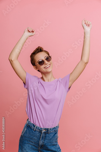 Young short-haired beautiful smiling woman in sun glasses dancing