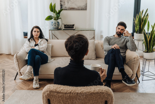 Leinwand Poster Married couple sitting on opposite sides of couch during therapy session with ps