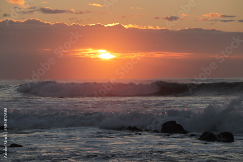 sunset between clouds on a wavy beach © Solene