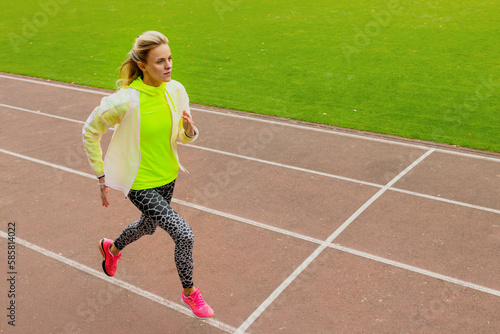 Running training at the stadium on the street. A young woman runs along the path