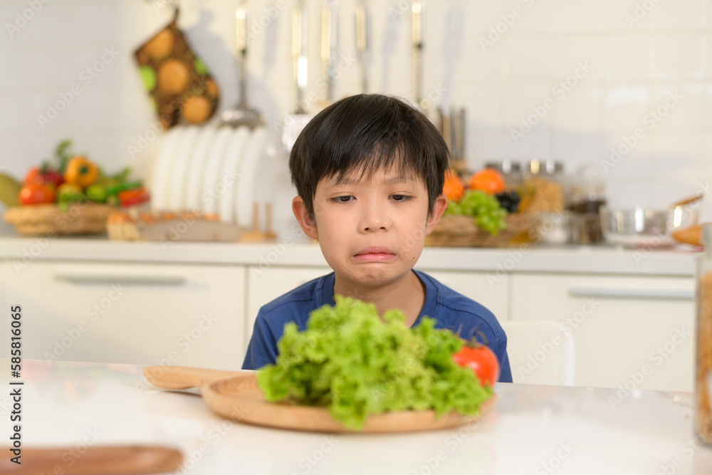 Asian boy feeling bored , unhappy to eat vegetables , health care concept Asian boy feeling bored , unhappy to eat vegetables , health care concept
