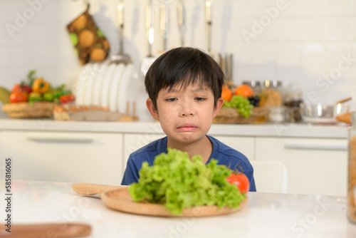 Asian boy feeling bored , unhappy to eat vegetables , health care concept