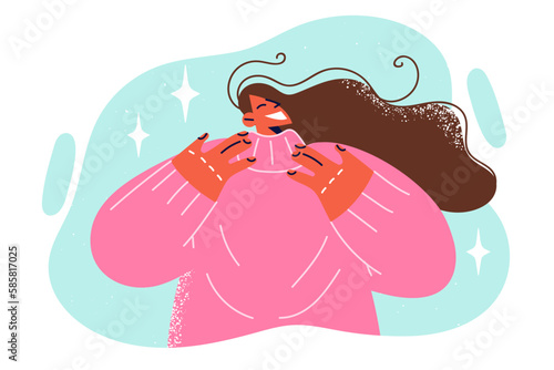 Positive woman smiles as she tries on warm sweater necessary for winter unheated rooms