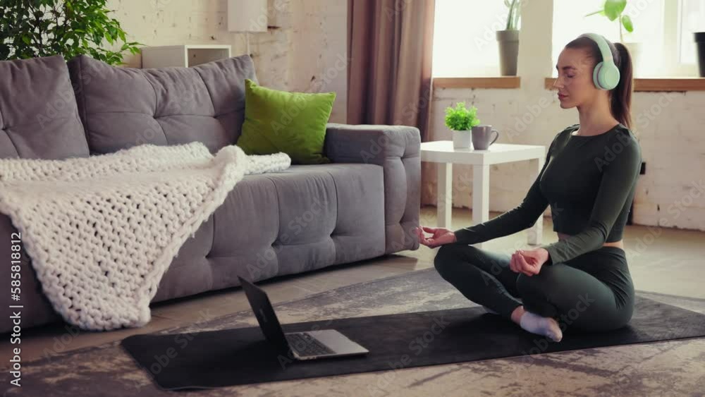 Calm, beautiful, young girl in sportswear sitting on fitness man in headphones, listening to online meditations. Yoga training at home. Concept of sportive and healthy lifestyle, wellness, care. Calm, beautiful, young girl in sportswear sitting on fitness man in headphones, listening to online meditations. Yoga training at home. Concept of sportive and healthy lifestyle, wellness, care.
