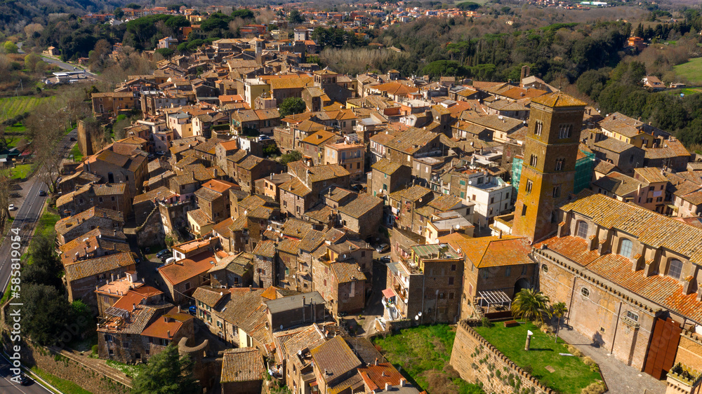 Aerial view of the historic center of Sutri, near Viterbo and Rome, Italy. The Romanesque cathedral with its bell tower dominates the city. All houses have traditional red tiled roofs in the old town.