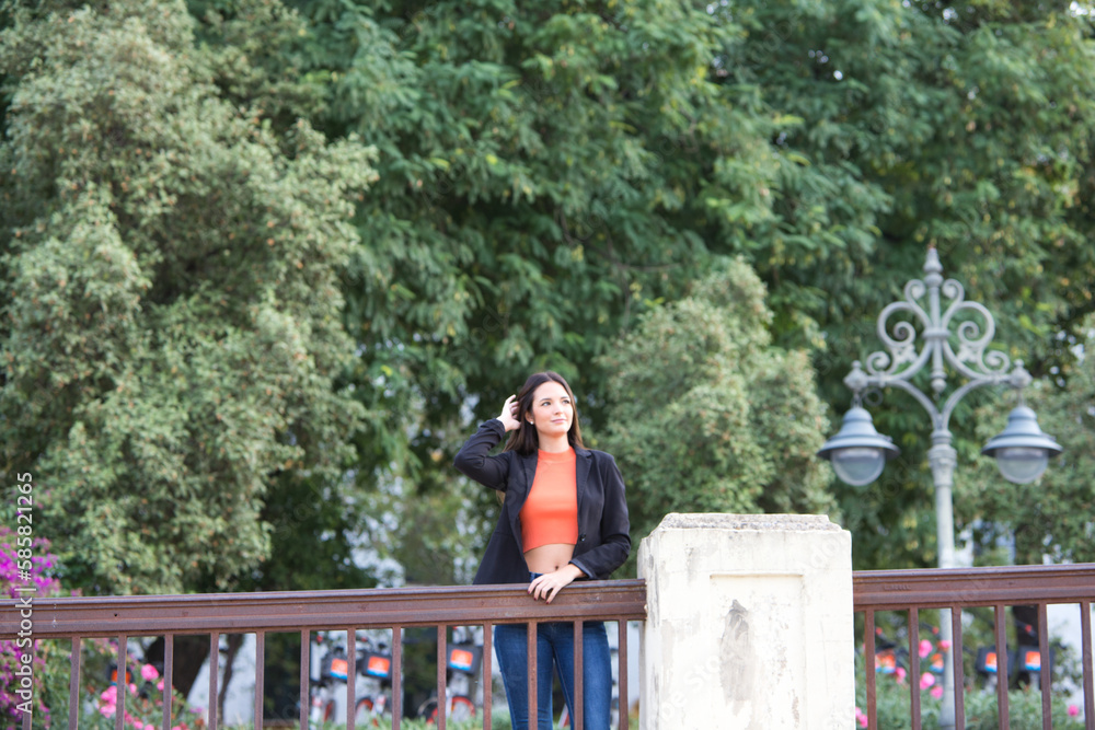 Fototapeta premium pretty young Spanish woman looking over the railing to the horizon. The woman is happy and content because she looks to the future with interest.