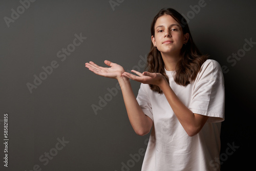 Casual teen girl showing blank copy space, on dark background photo