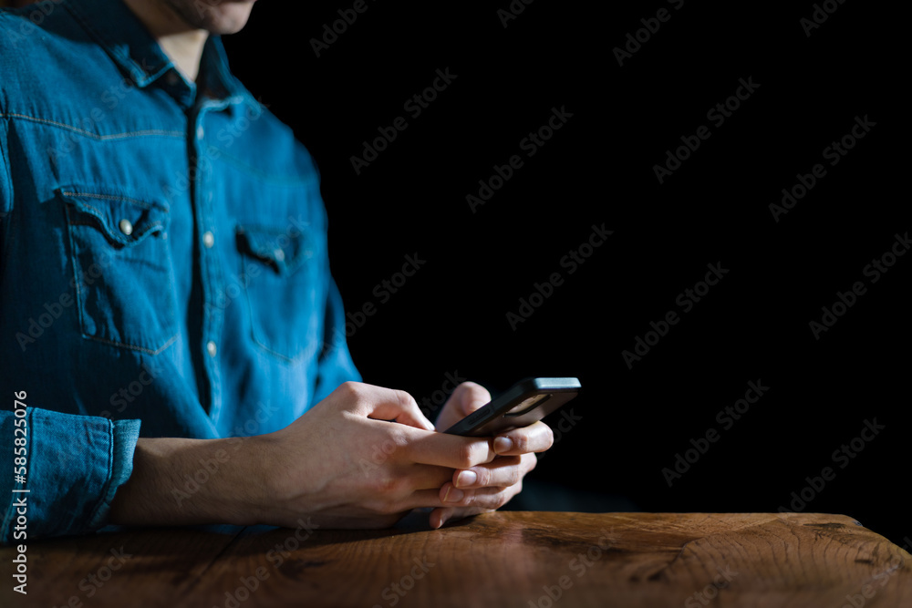 Man typing on his phone with two fingers in the dark. Chatting on the internet concept. Consuming content online. Using smartphone in the dark blue light danger. Man typing on his phone with two fingers in the dark. Chatting on the internet concept. Consuming content online. Using smartphone in the dark blue light danger.