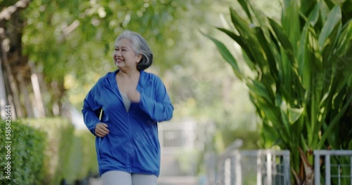 Asian senior woman warming up and jogging in the park. Health care for the elderly. Exercise activities to keep your body healthy. Concept Workout