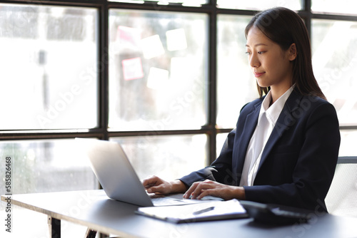 Businesswoman working with financial documents on laptop on office desk.