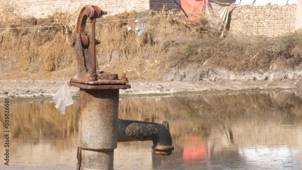 Rusty Metal Water Pump In Rural Sindh Beside Low Lying Water At Pond Rusty Metal Water Pump In Rural Sindh Beside Low Lying Water At Pond