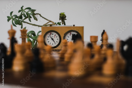 Wooden chess pieces and timer clock behind them