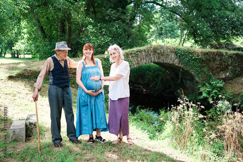 Caucasian family of three generations for a walk in the countryside, grandfather, mother and pregnant daughter, happily smile at the arrival of the 4th generation. family relationship concept.