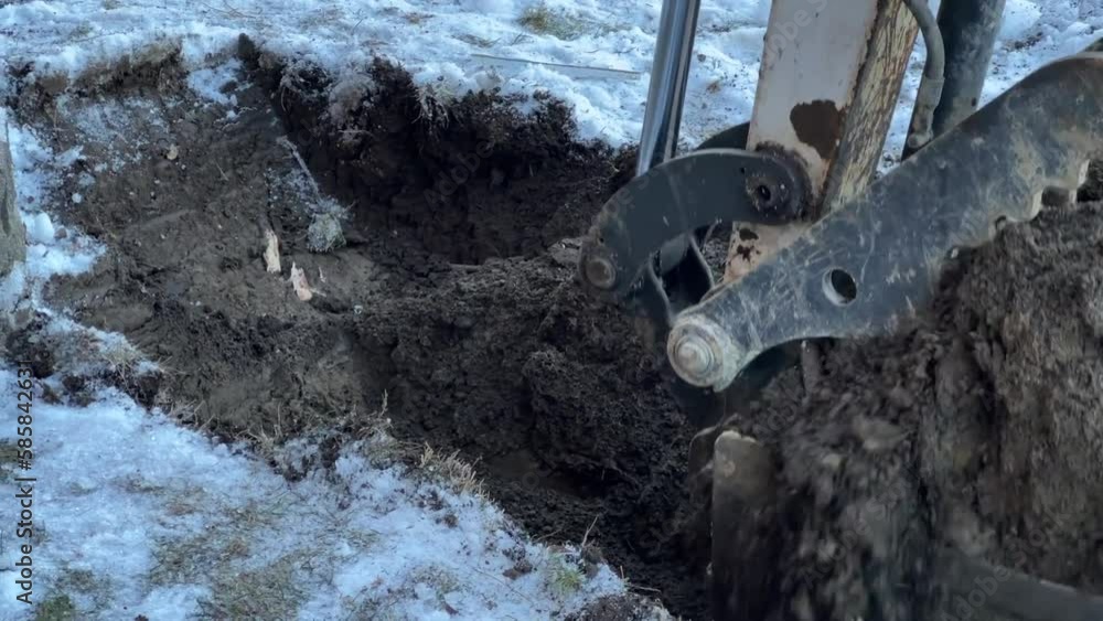 Excavator digging in frozen earth, robust construction machine is