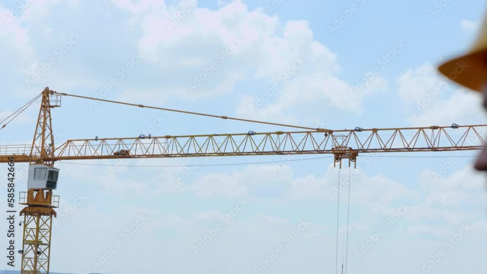 Male worker control construction crane. Foreman in yellow helmet standing at construction site. Building concept. Real time video Male worker control construction crane. Foreman in yellow helmet standing at construction site. Building concept. Real time video