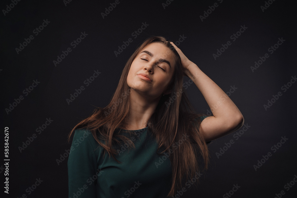 Portrait of young woman in studio, black background.