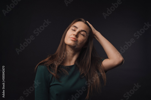 Portrait of young woman in studio, black background.