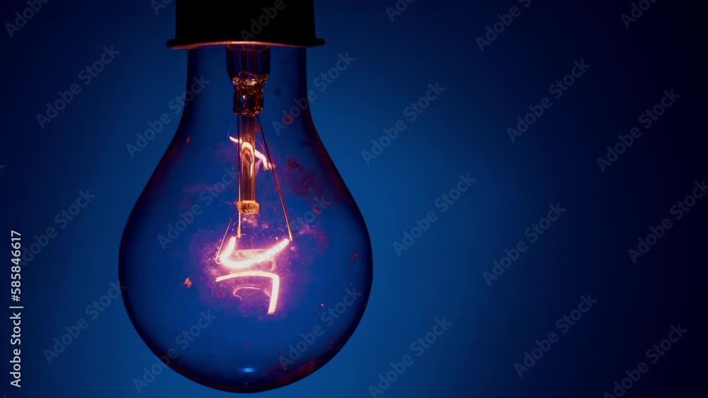 Light bulb flashes on a blue background in the dark. Slow turning on