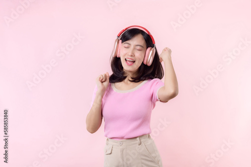 Smile pretty model person listen music song and enjoy dance with wireless headphone online audio radio sound. Positive fun exited joyful youth female woman sing on pink isolated background studio © Jirawatfoto