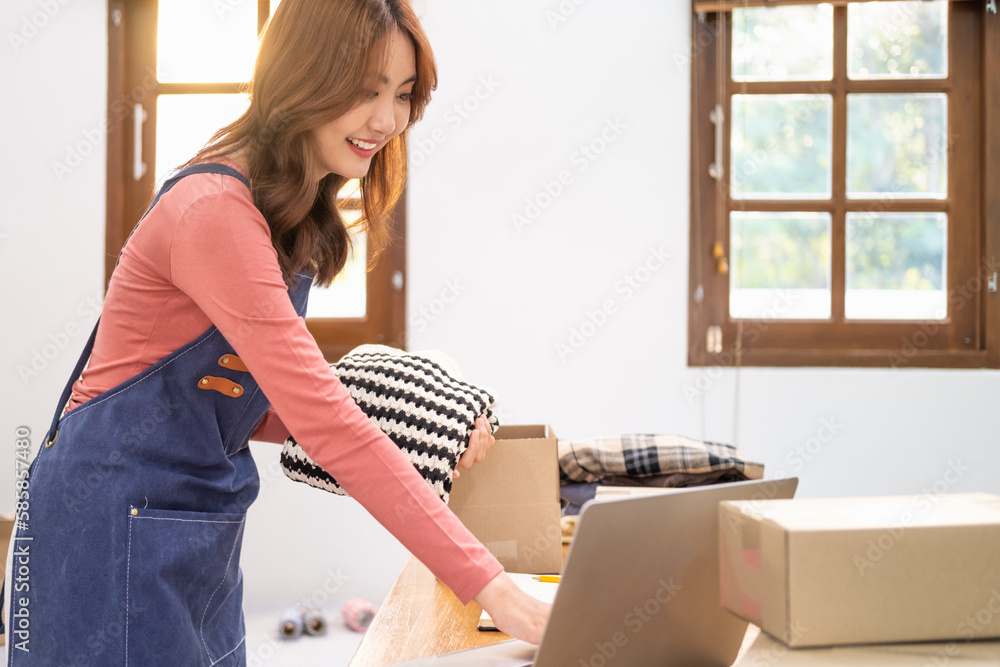 Young business woman working online e-commerce shopping at shop. Young woman seller prepare parcel box of product for deliver to customer. Online selling, e-commerce.SME business entrepreneurs ideas, Young business woman working online e-commerce shopping at shop. Young woman seller prepare parcel box of product for deliver to customer. Online selling, e-commerce.SME business entrepreneurs ideas,