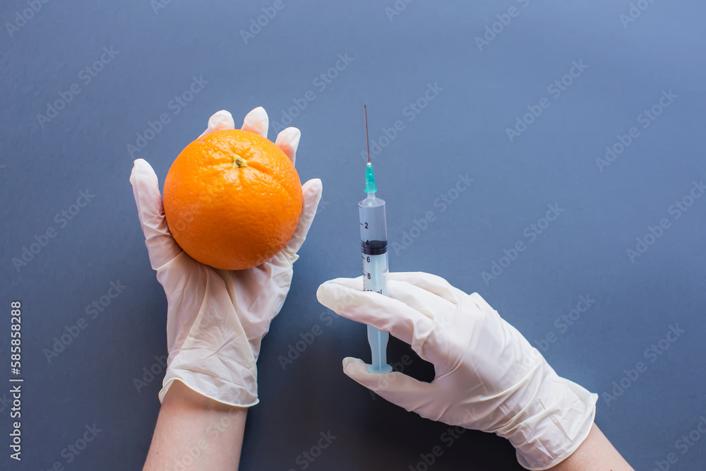 GMO concept. Orange in hands modified by injecting GMO concept. Orange in hands modified by injecting
