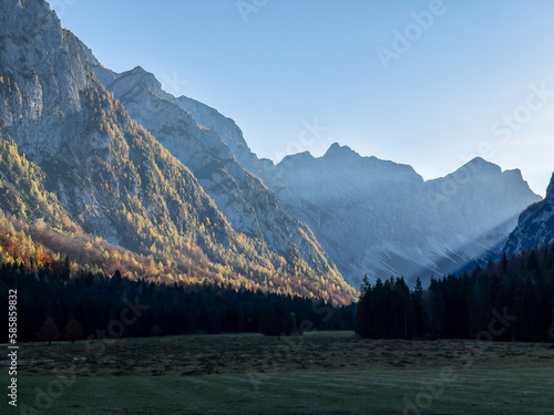 Golden glowing larch trees on mountain slopes above picturesque Krma Valley photo