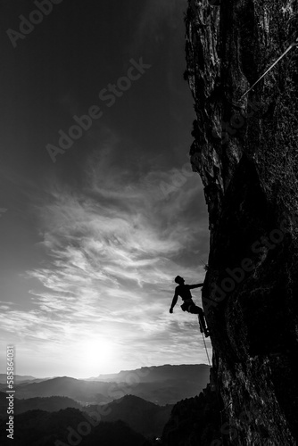 boy climbing at sunset in the mountains with the forest in the background, copy space, business, security, trust, black and white