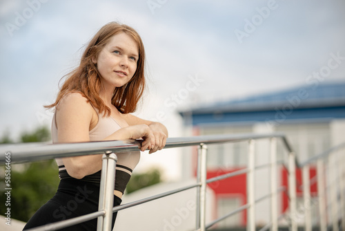 the girl stands on the stairs and leans on the railing