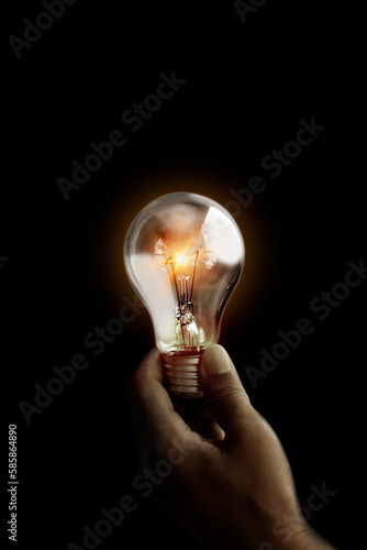 Light bulb glowing hold in hand on black background. Concept of saving electricity