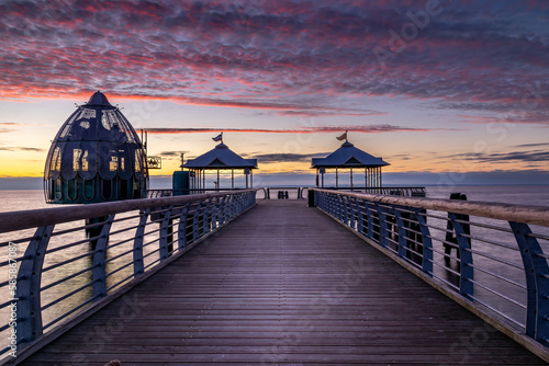 Seebrücke mit Tauchgondel in Grömitz beim Sonnenaufgang. Wolken werden rot angeleuchtet