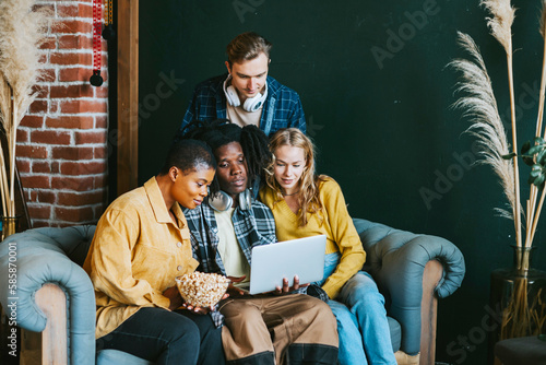 diversity and international group of young people students watching movie on laptop having fun together eating popcorn in college dorm photo