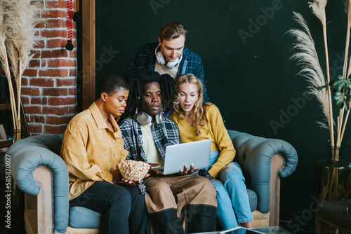 diversity and international group of young people students watching movie on laptop having fun together eating popcorn in college dorm photo