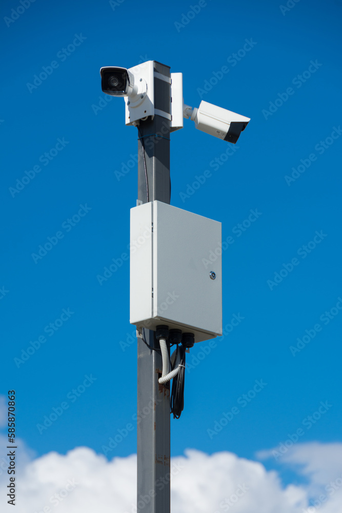 white security cameras on a gray metal pole on a bright sunny day white security cameras on a gray metal pole on a bright sunny day