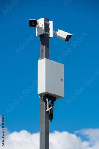 white security cameras on a gray metal pole on a bright sunny day