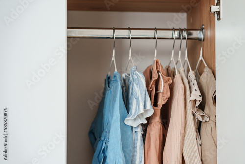 Children's clothes, girls' dresses hang on hangers in an open closet, dressing room