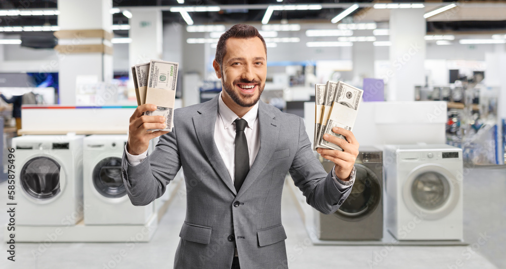 Young businessman holding money and smiling in an electrical appliance shop Young businessman holding money and smiling in an electrical appliance shop
